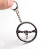 Red and chrome racing steering wheel keychain on white background